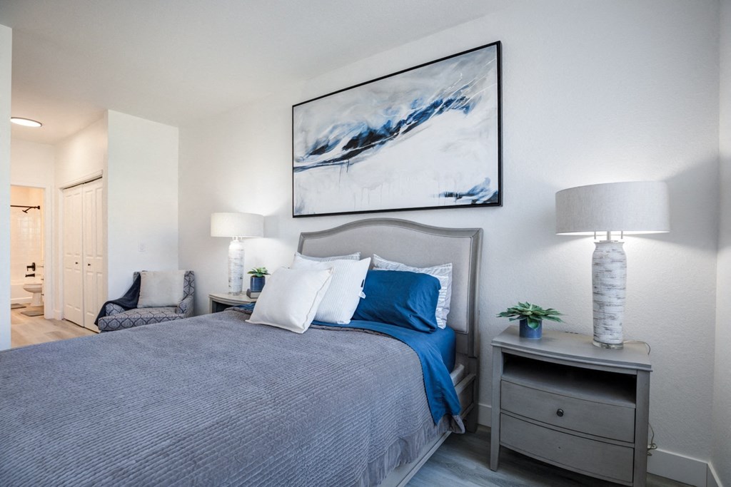 a bedroom with a large bed and a painting on the wall