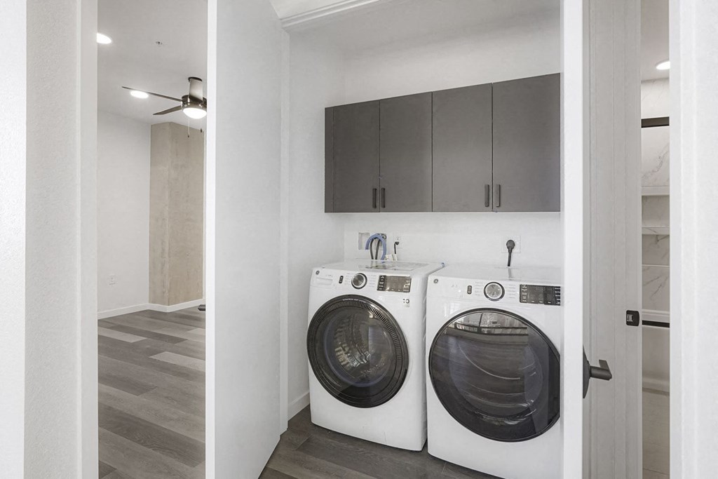a washer and dryer in a laundry room with white cabinets