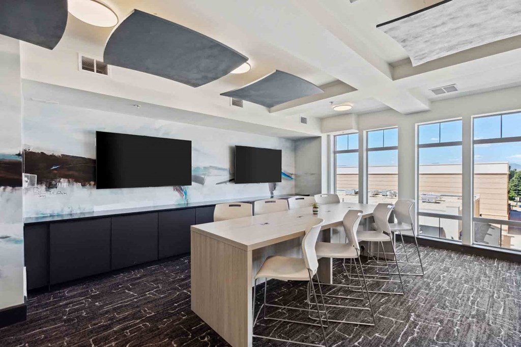 a conference room with a long table and chairs and televisions