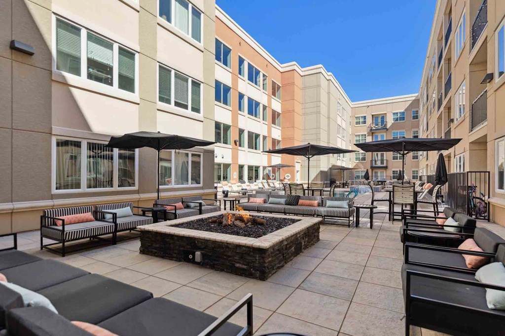 a patio with chairs and umbrellas and a fire pit