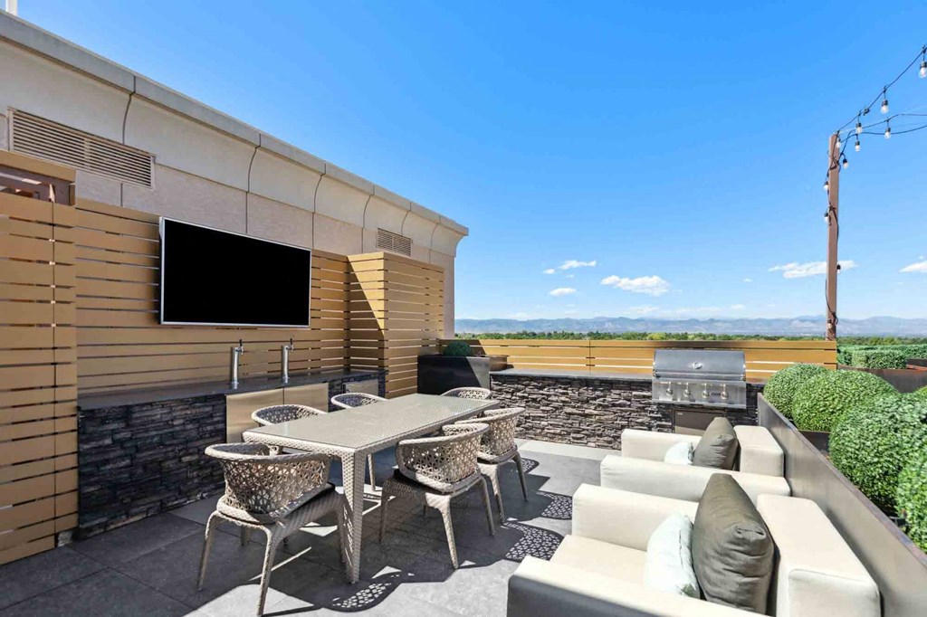a patio with furniture and a grill on the side of a building