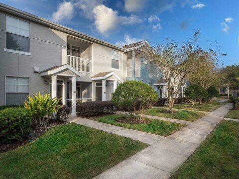 A row of townhouses with a sidewalk in front.