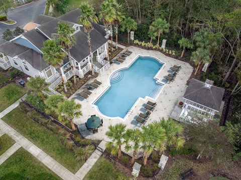 A large swimming pool surrounded by a white fence and palm trees.