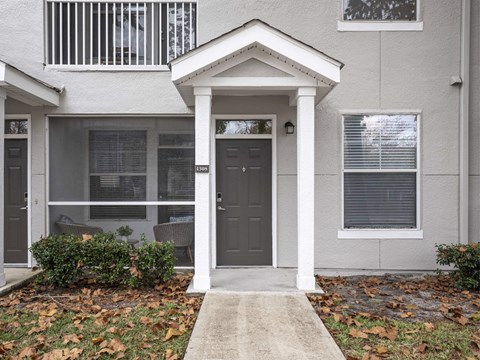 A grey house with a black door and a small porch.