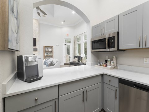 A kitchen with a white countertop and grey cabinets.