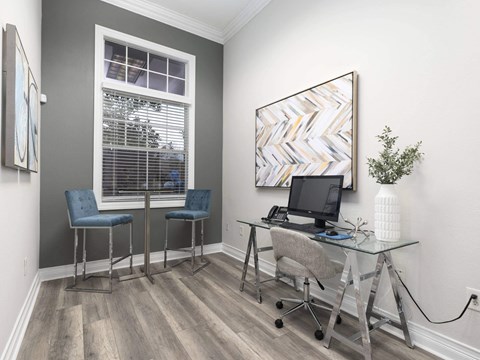A room with a desk, two chairs, and a painting on the wall.