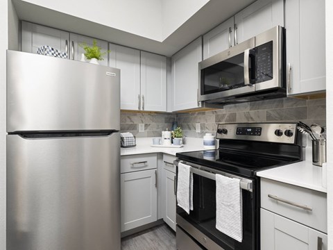 A modern kitchen with a stainless steel refrigerator and black stove.