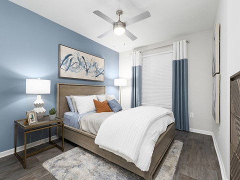 A bedroom with a bed, nightstand, and a ceiling fan.