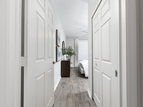 A long hallway with white doors and a brown suitcase on the floor.