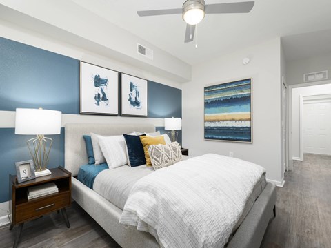 A bedroom with a bed, nightstand, and artwork on the wall.