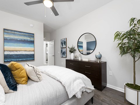 A bedroom with a bed, dresser, and a painting on the wall.