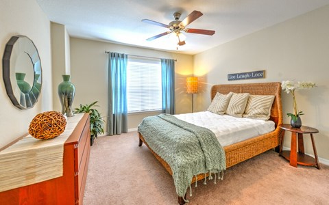 A bedroom with a bed, a ceiling fan, and a mirror on the wall.