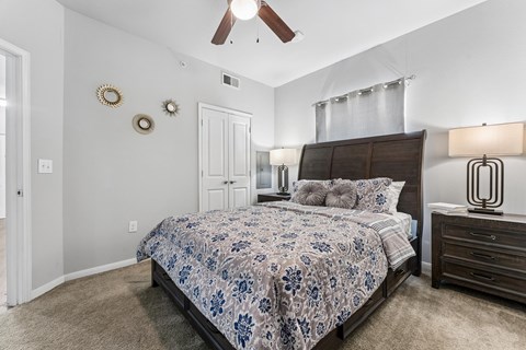 A bedroom with a bed, dresser, and ceiling fan.