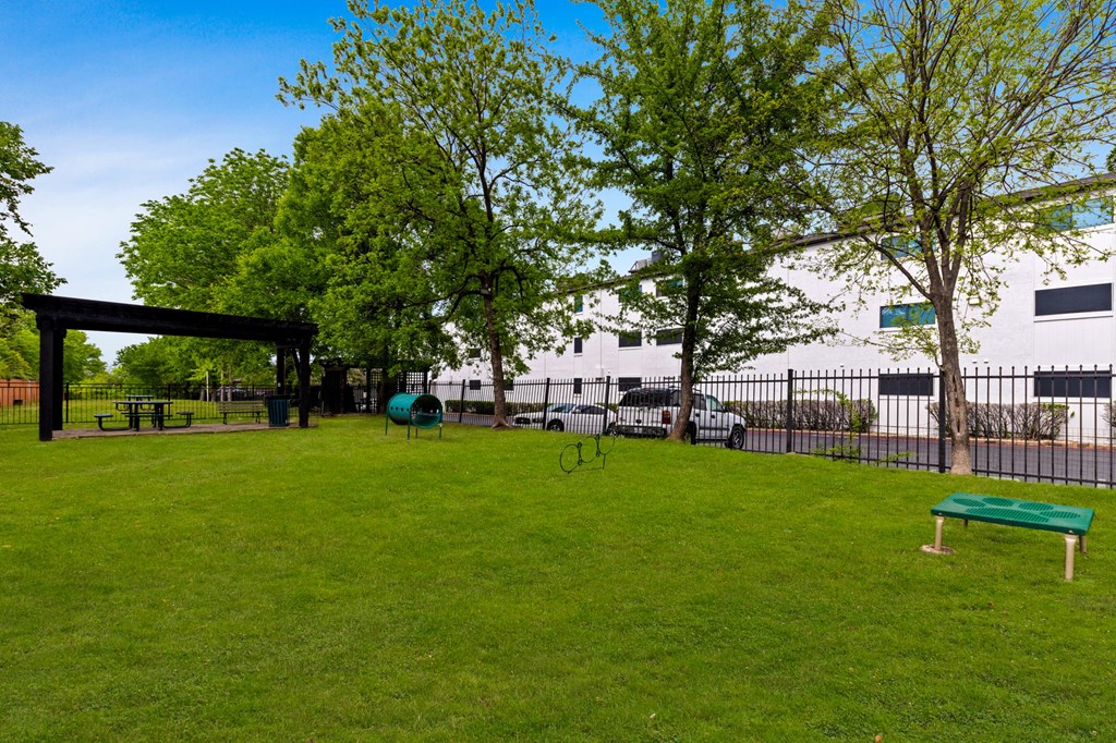a park with green grass and trees in front of a building