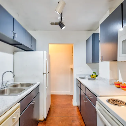 A kitchen with a white fridge and a white sink.