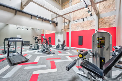 A gym with a variety of exercise equipment including treadmills, stationary bikes, and weight machines.