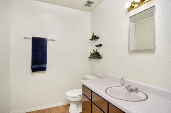 A white bathroom with a toilet, sink, and mirror.