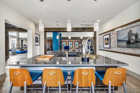 A kitchen with a large island and blue chairs.