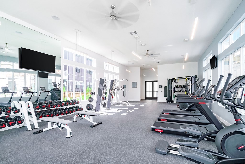 a spacious fitness room with cardio equipment and a flat screen tv