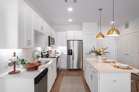 a large white kitchen with stainless steel appliances and white cabinets