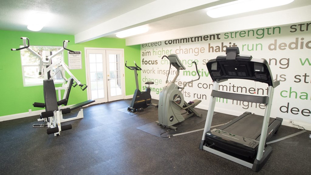 a gym with exercise equipment and green walls