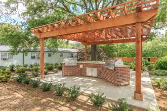 a backyard with a brick barbecue and a wooden pergola