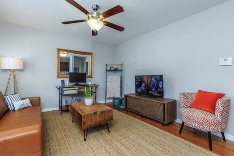 a living room with a couch and a tv and a ceiling fan