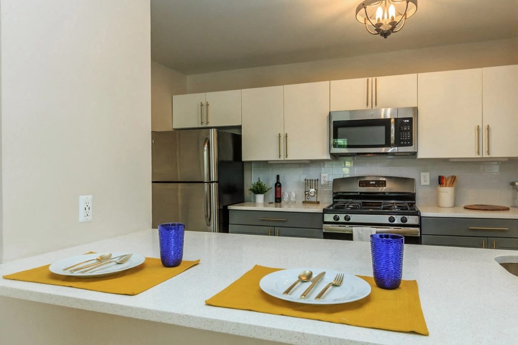 a kitchen with white cabinets and a white counter top with yellow place mats and purple vases