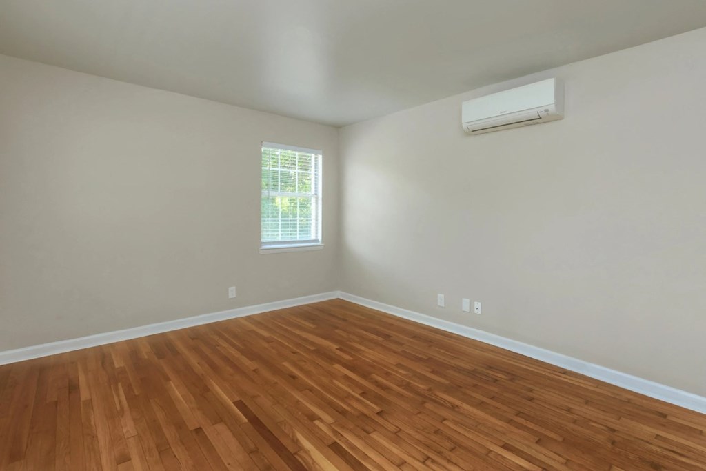 an empty room with a window and wooden floors