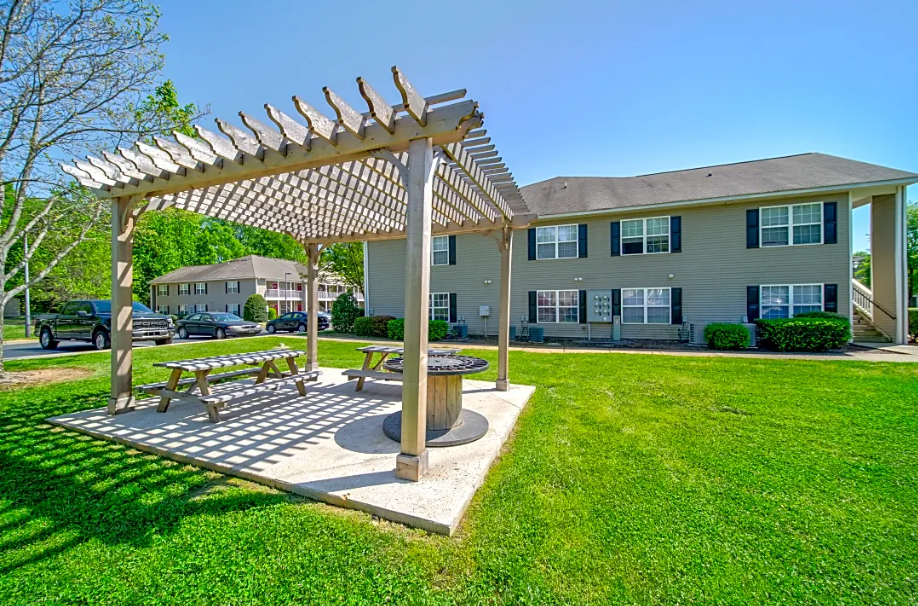 a picnic area with a pergola in front of an apartment building