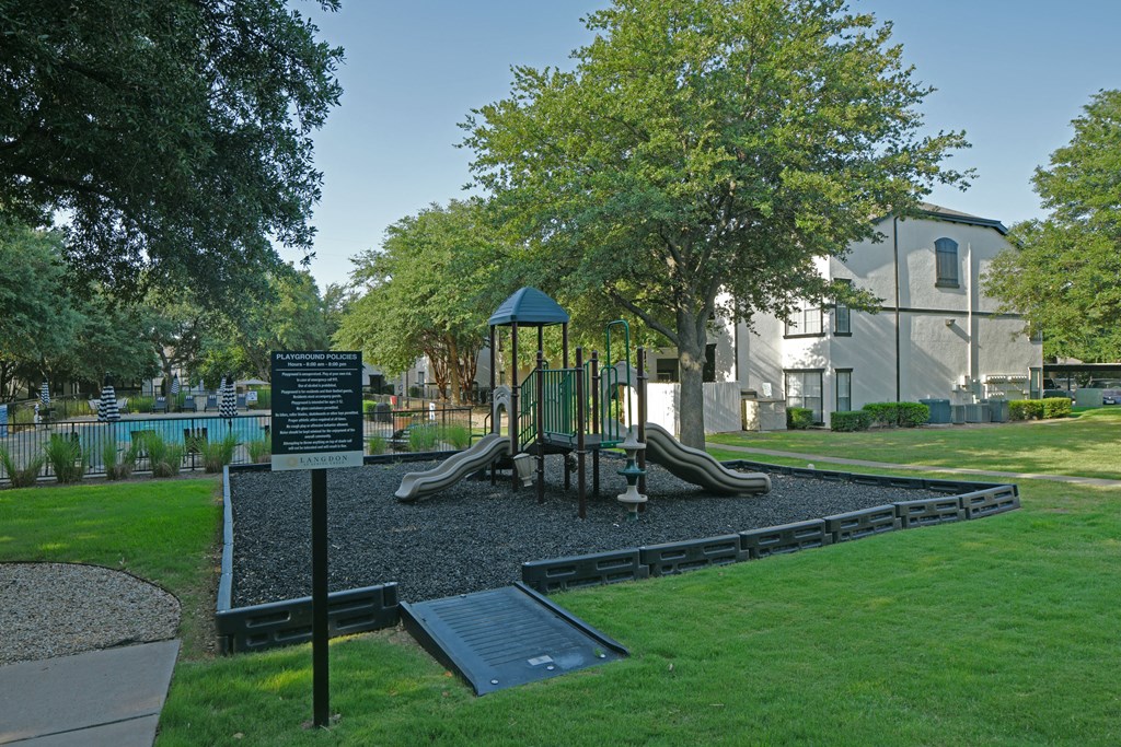 a park with a playground and a sign in front of a building