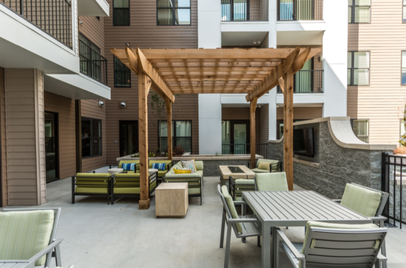a patio with wooden furniture and a large wooden pergola