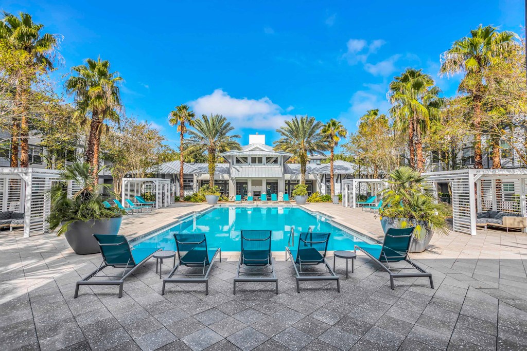 the pool is surrounded by chairs and palm trees