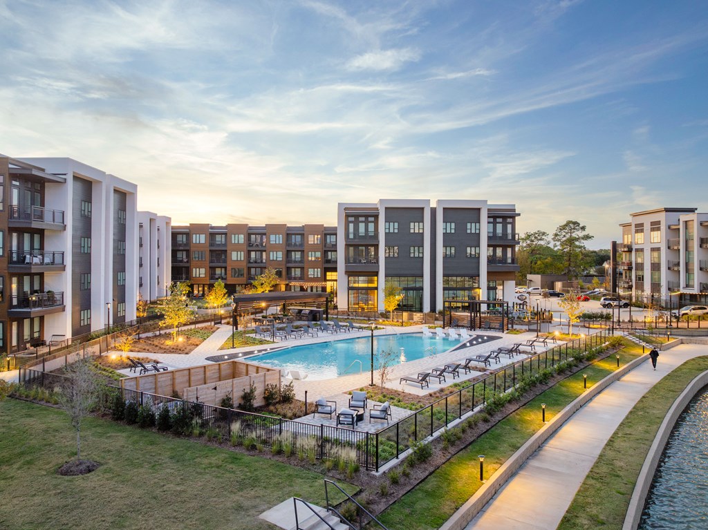 A modern apartment complex with a pool and a walking path.