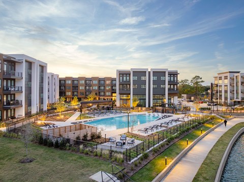 A modern apartment complex with a pool and a walking path.