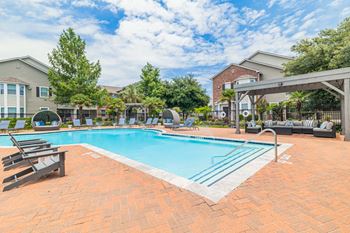 A swimming pool surrounded by lounge chairs and umbrellas.
