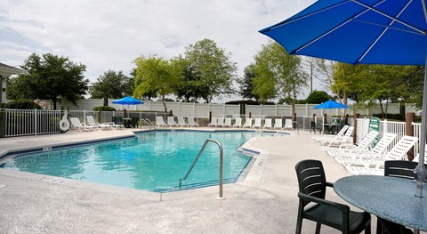 A pool area with chairs and umbrellas.
