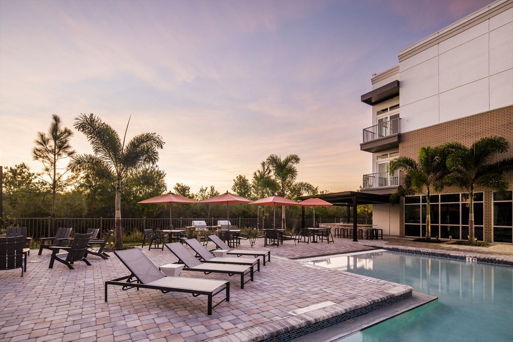 a swimming pool with lounge chairs and umbrellas next to a building