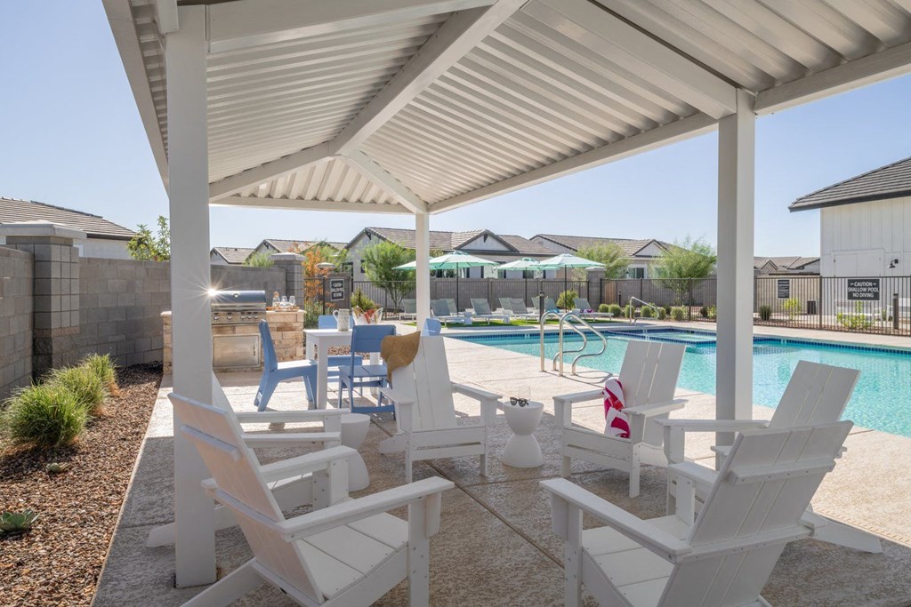 A white patio with chairs and a pool.