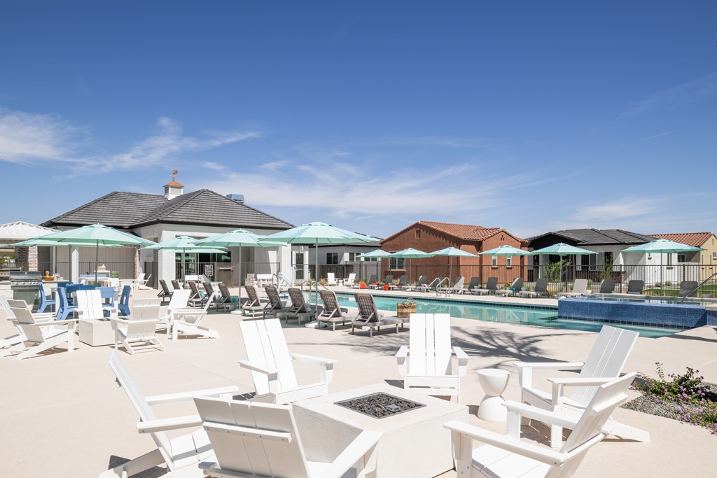 A pool area with white chairs and umbrellas.