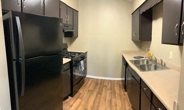 a kitchen with a black refrigerator freezer next to a stove top oven