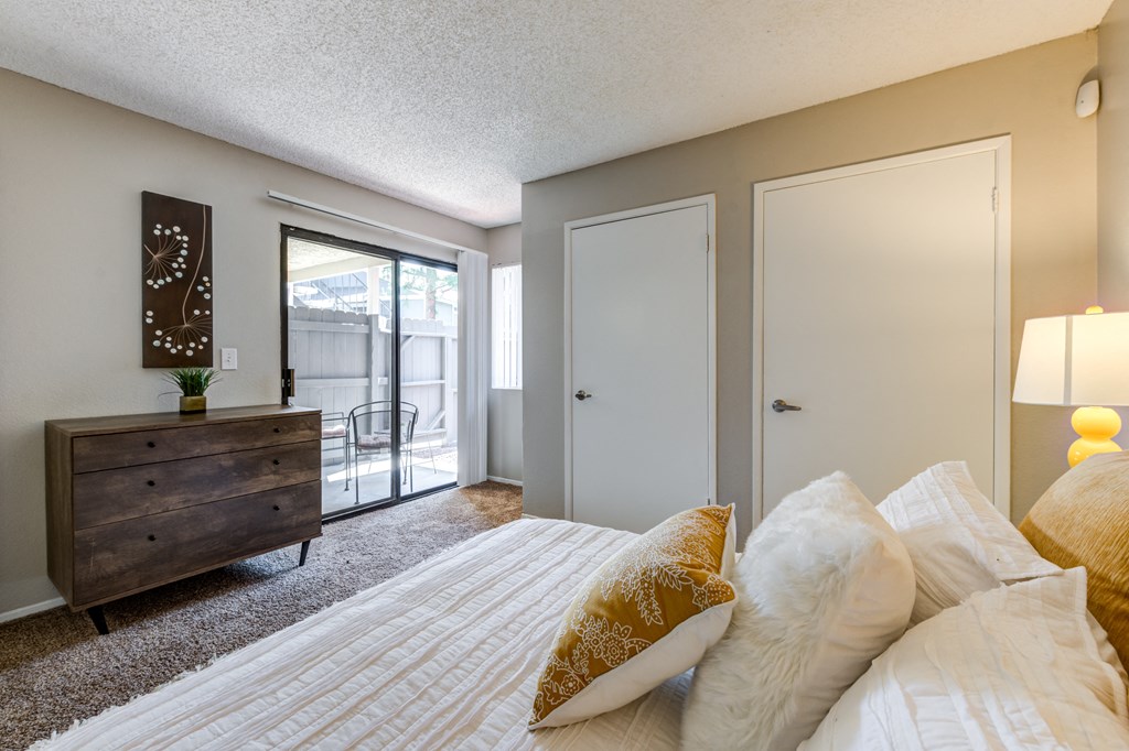 A bedroom with a bed, dresser, and sliding glass doors.