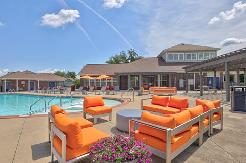A poolside area with orange chairs and a clear blue sky.