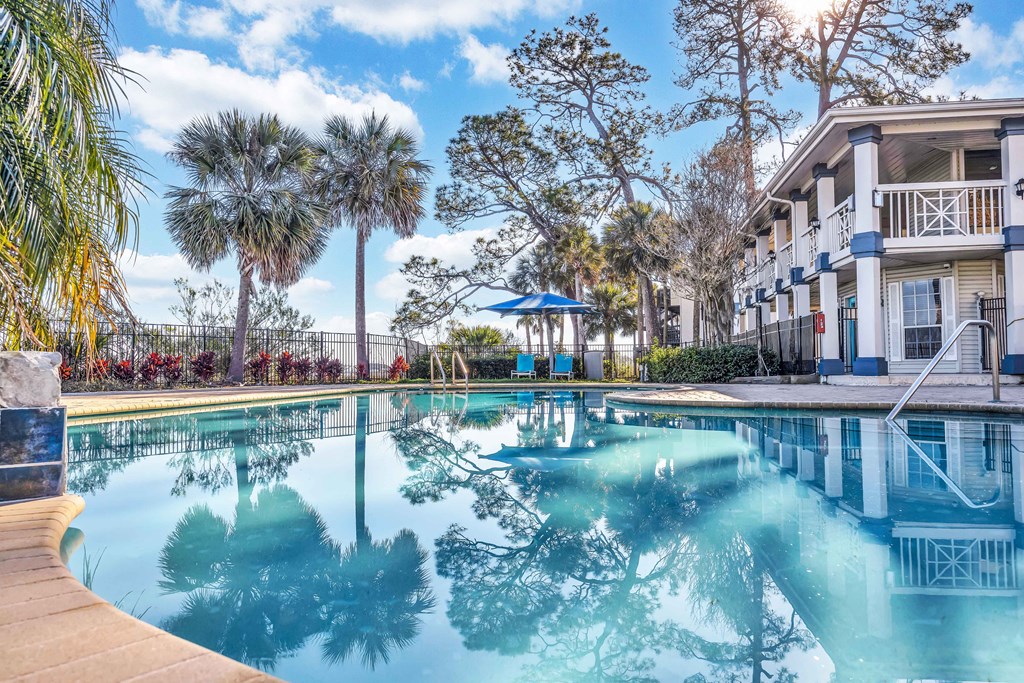 a swimming pool with palm trees and a building in the background