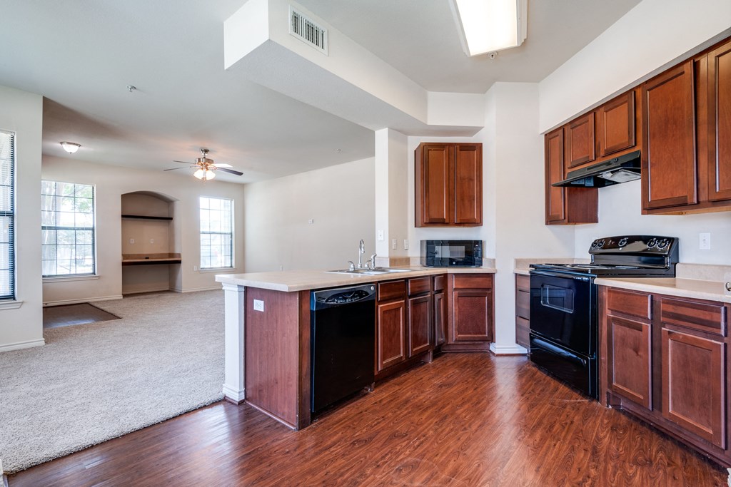 an empty kitchen with wooden cabinets and black appliances