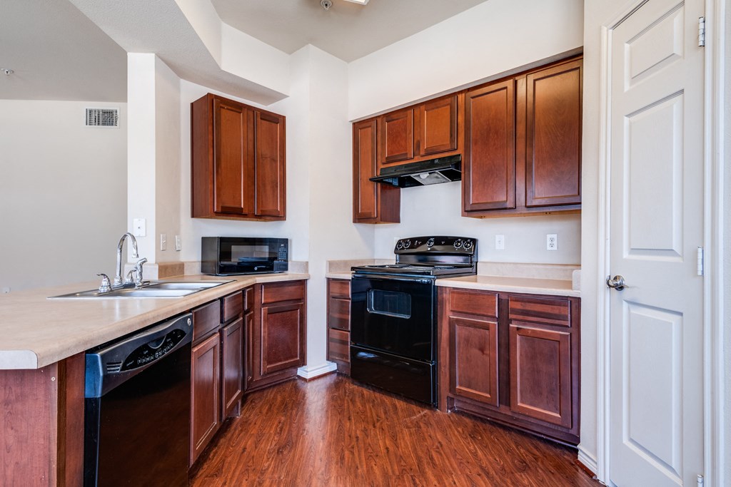 an empty kitchen with wooden cabinets and a black stove and oven