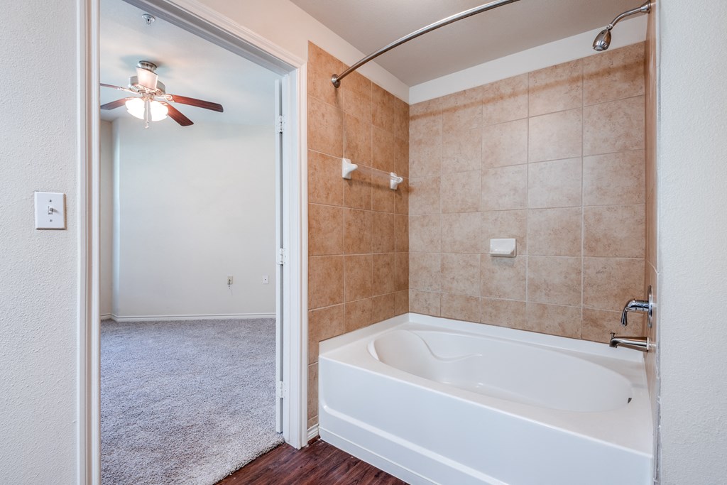 a bathroom with a large tub and a ceiling fan