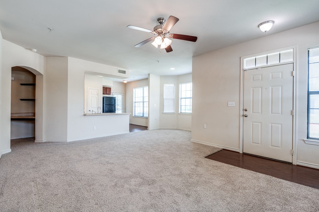 an empty living room with a ceiling fan