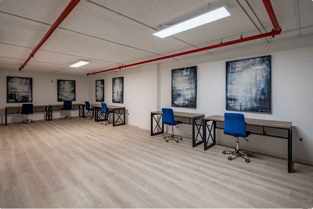 an empty classroom with chairs and desks and paintings on the wall