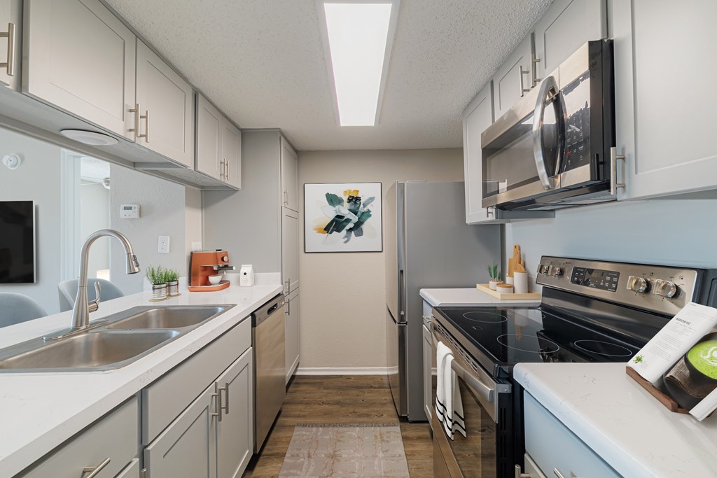 A kitchen with a stove, sink, and refrigerator.